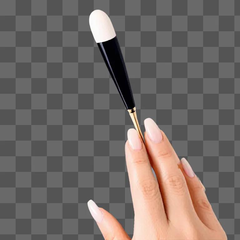 A hand with long nails holds a makeup brush